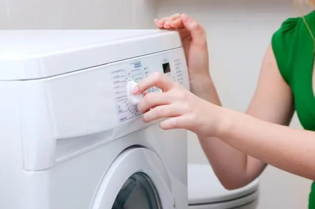 Девушка устанавливает режим стиральной машины.