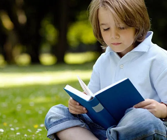 Мальчик читает на траве