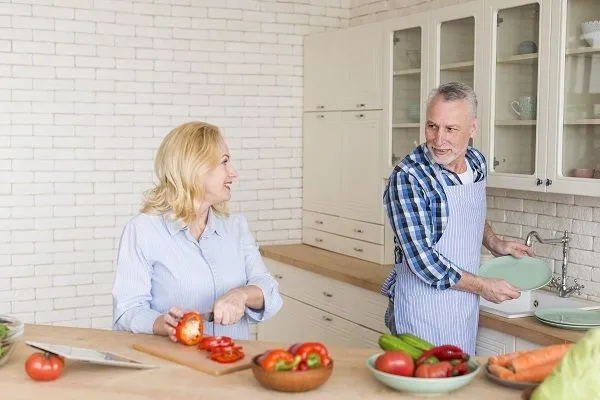 Мужчина моет посуду и помогает своей женщине на кухне, проявляя к ней уважение