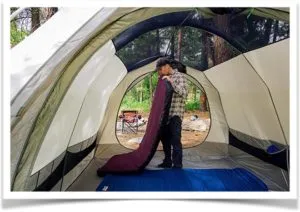 Мужчина надувает матрас в палатке