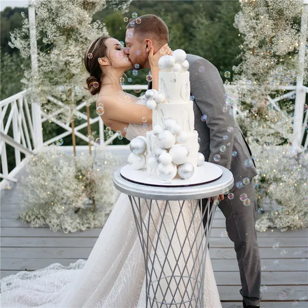 Молодожёны целуются возле свадебного торта 