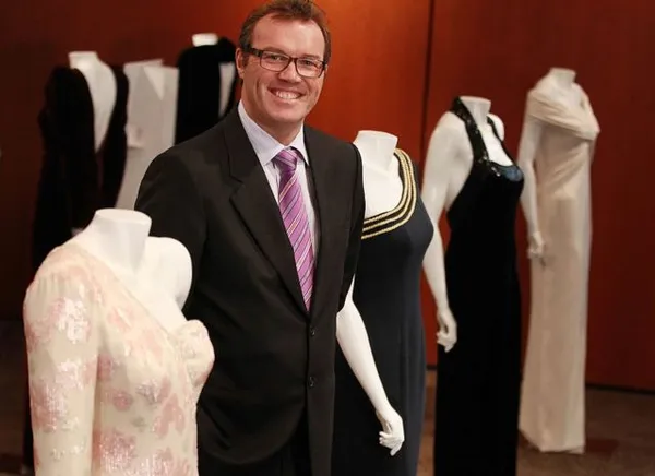 Эндрю Мортон на фоне платьев Дианы, выставленных в Торонто