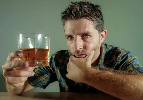 мужчина в рубашке со стаканом алкоголя
