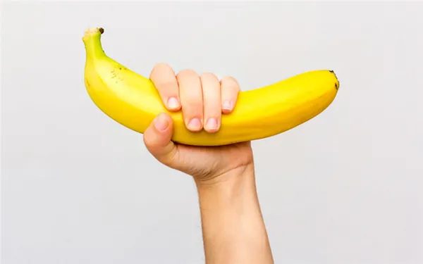 Рука крепко держит банан на белом фоне